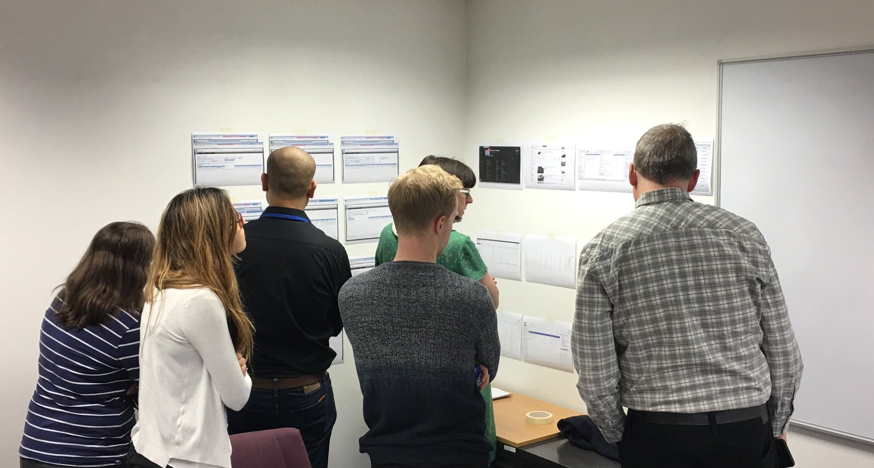 The team gathered at a wall of printed screens, reviewing the work together