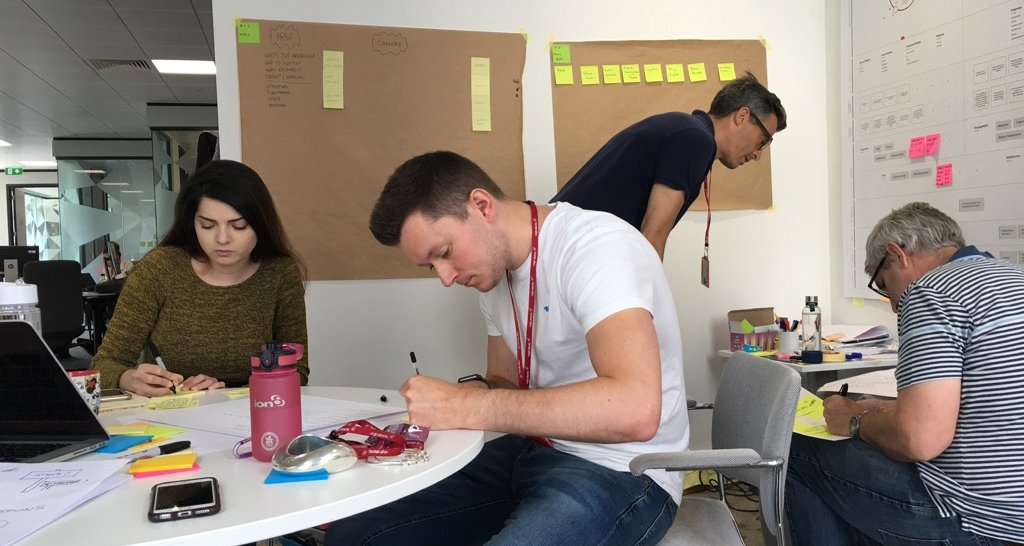 The design team at their desks, working, kraft-paper boards behind them