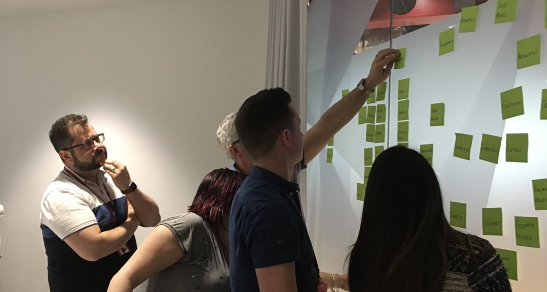 The Virgin Holidays design team clustering sticky notes on a glass wall together